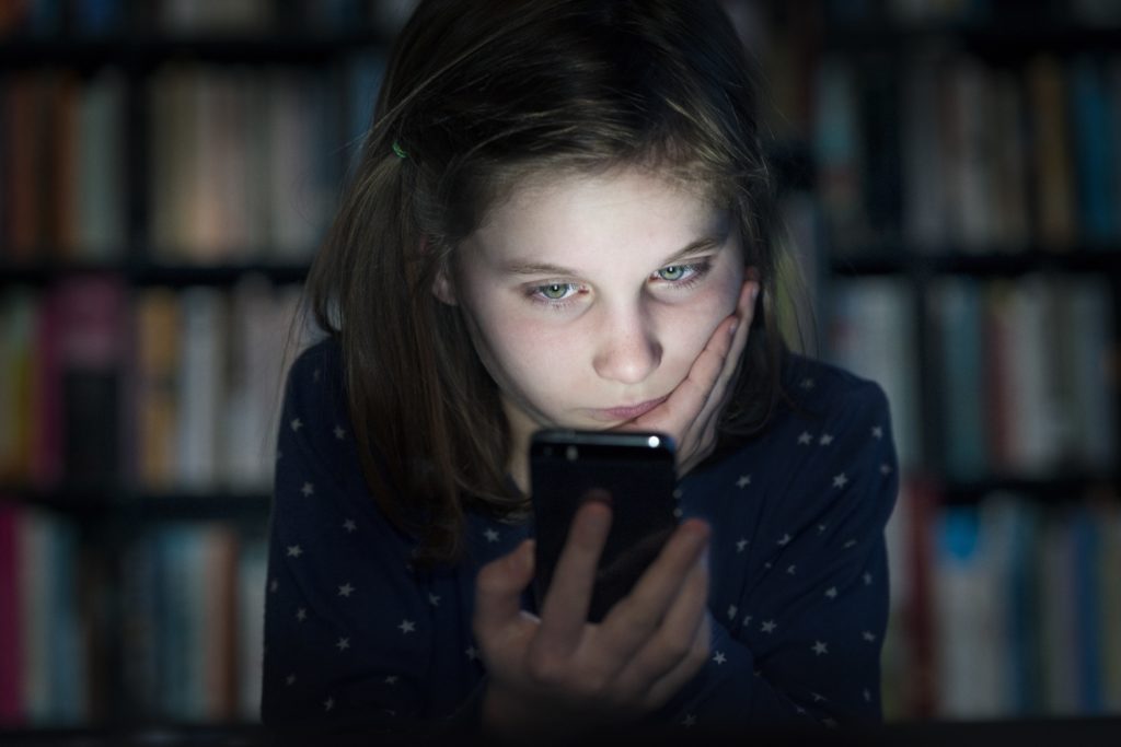 Young girl viewing unpleasant message on cell phone